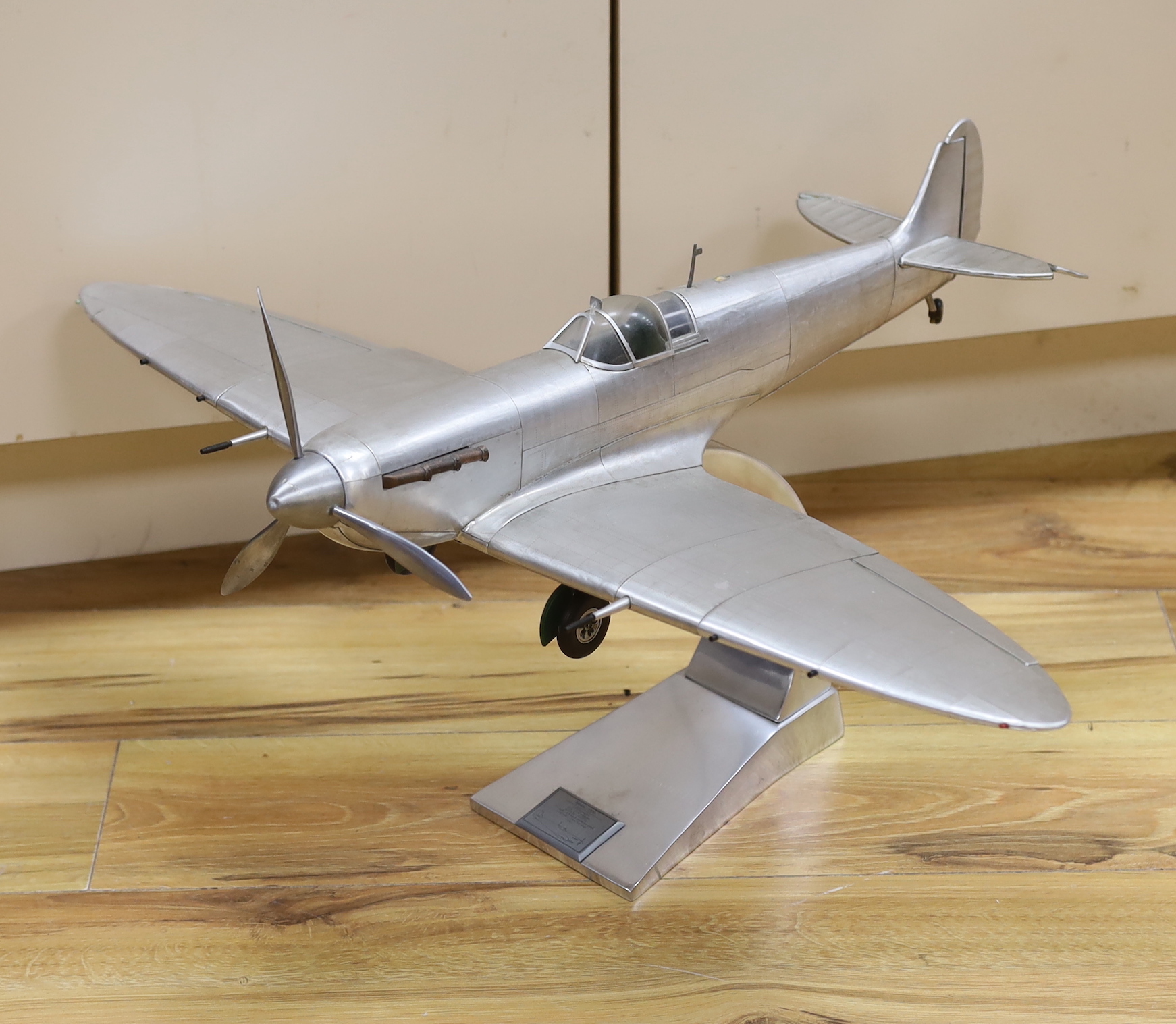 A sheet metal model of a WWII Spitfire on a stand, applied plaque to the base, 60cm in length